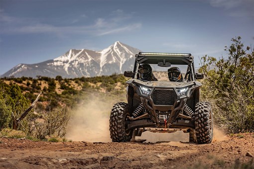 Front angle of a person and passengers driving a side x side off-road. opens in a new window
