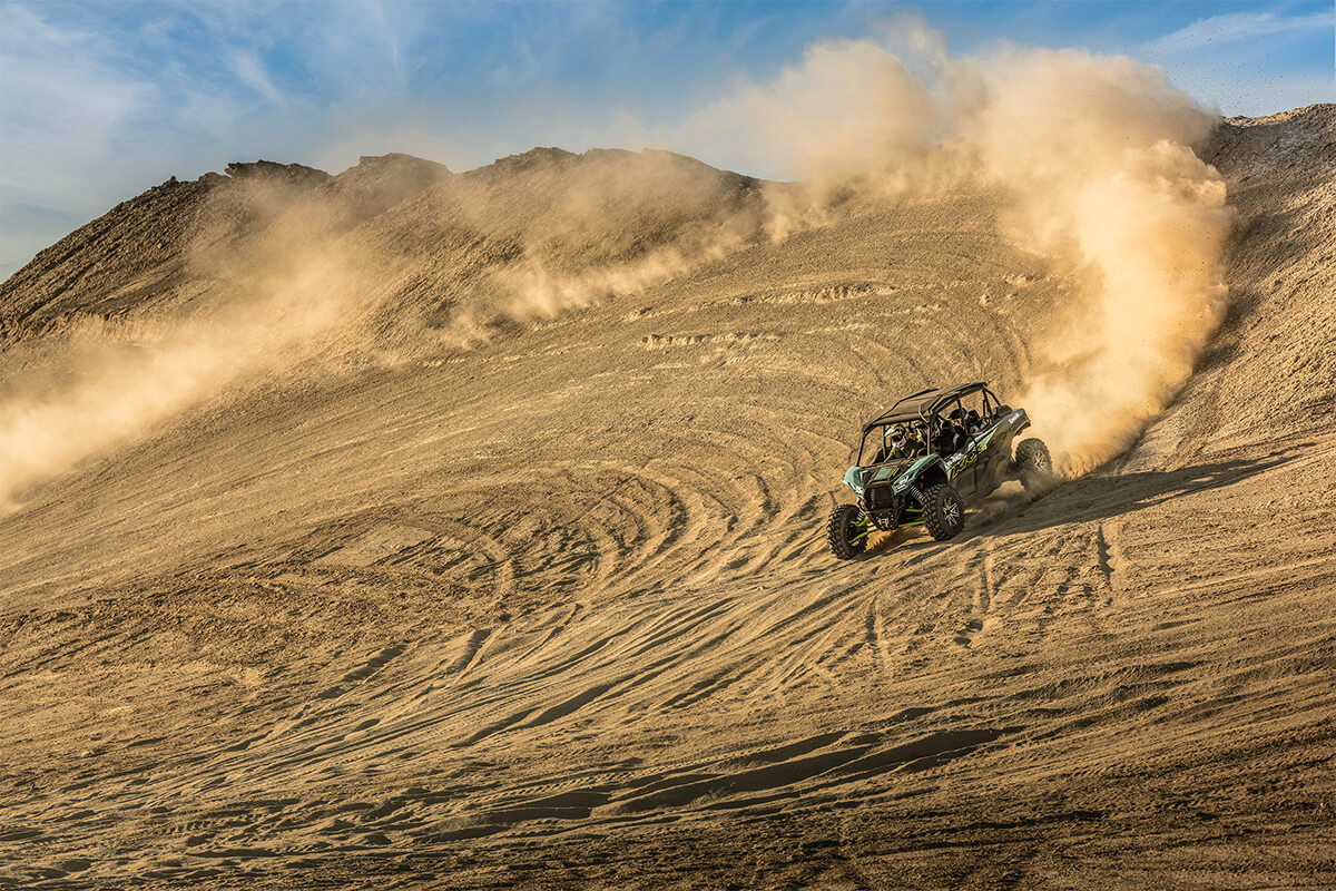 Three-quarter front angle of a person driving a side x side off-road down hill.