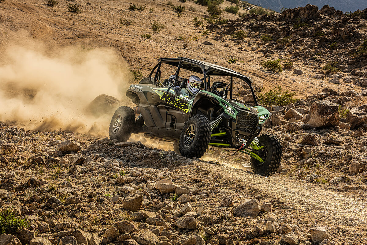 Three-quarter front angle of a person and passengers driving a side x side off-road around a corner.