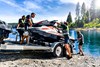 Side profile of four people unloading a personal watercraft from a utility trailer.