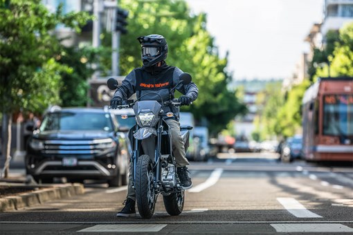 Front angle of a person sitting on a motorcycle at an intersection. opens in a new window