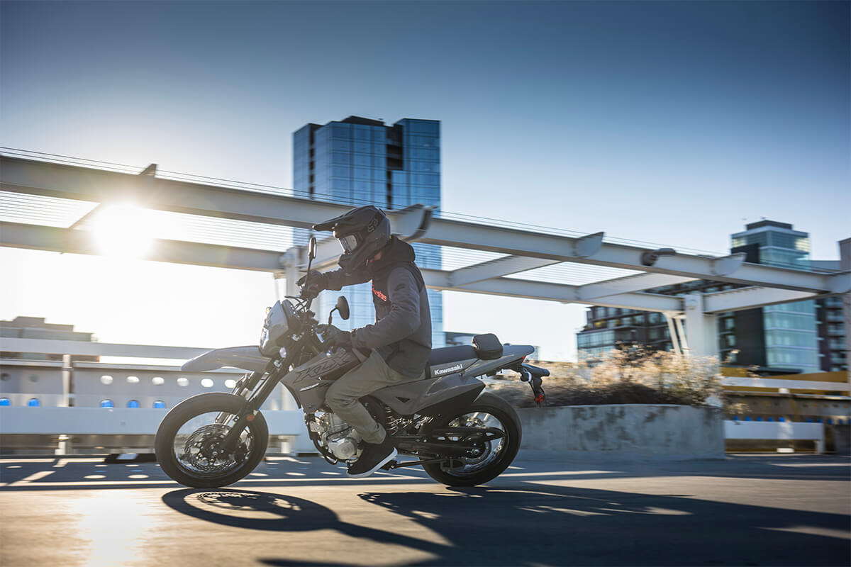 Side angle of a person riding a motorcycle in a city.