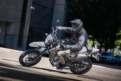 Three-quarter front angle of a person making a sharp turn on a motorcycle on a city street. opens in a new window