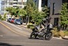 Three-quarter front angle of a person making a turn on a motorcycle on a city street.