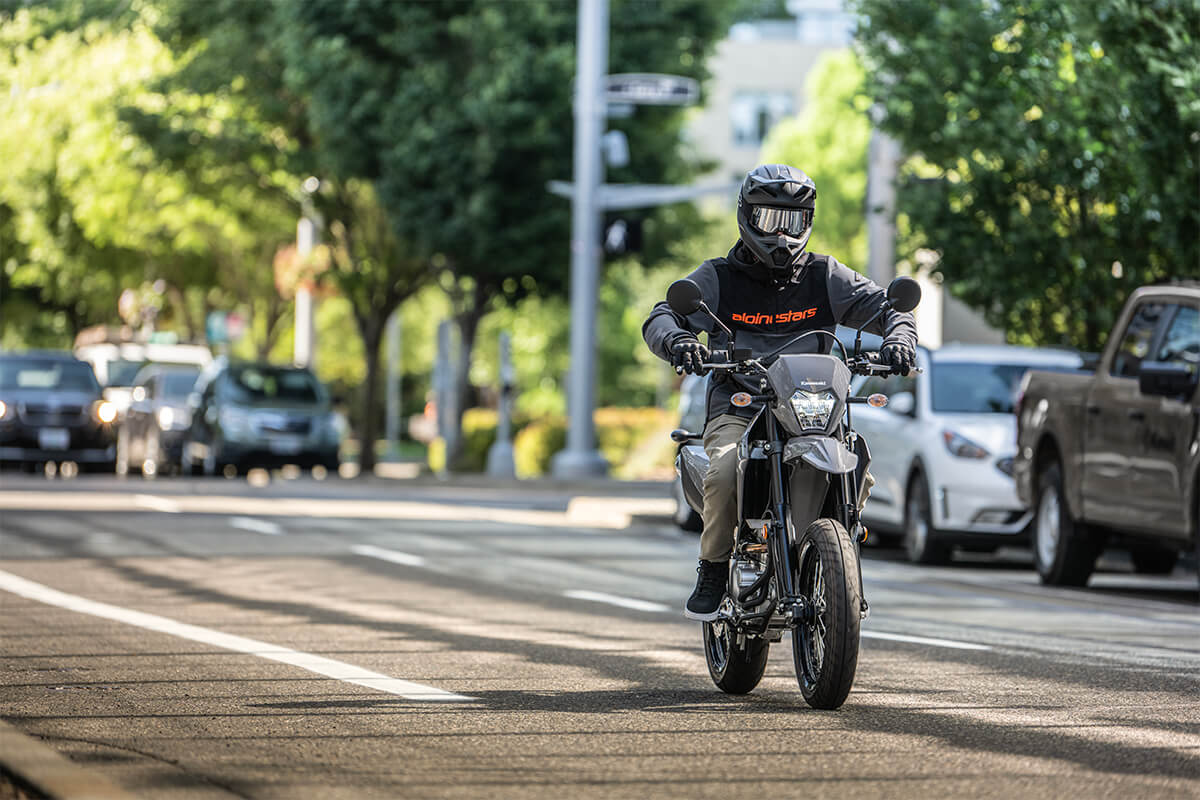 Three-quarter front angle of a person riding a motorcycle in a city.