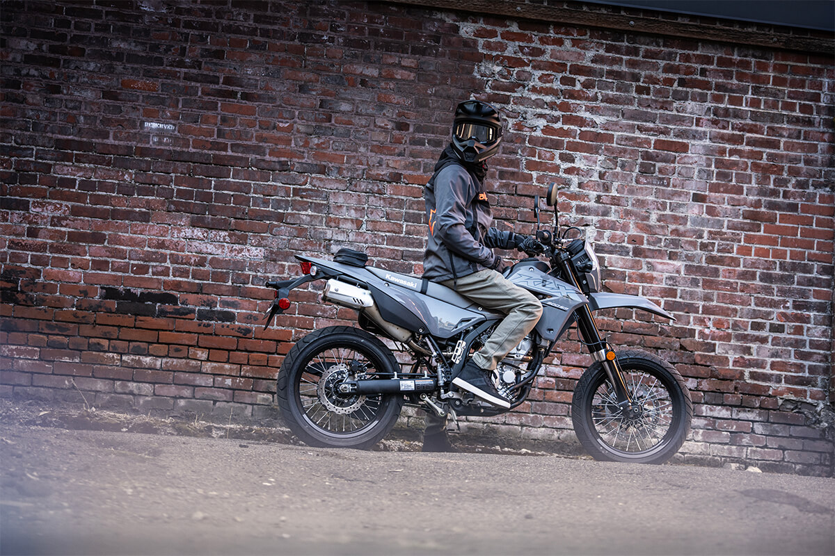 Side angle of a person looking back while sitting on a parked motorcycle.