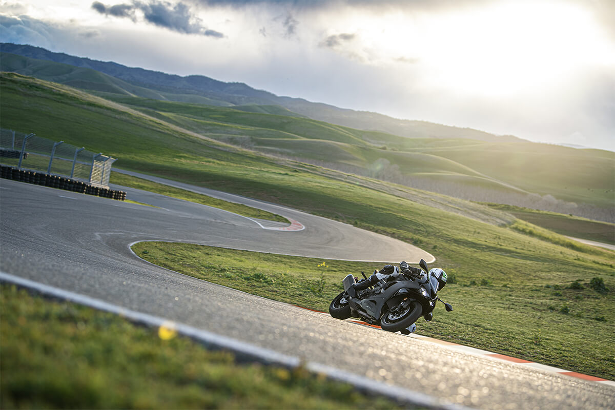 Three-quarter front angle from far away of a person riding a motorcycle through a series of turns on a track.