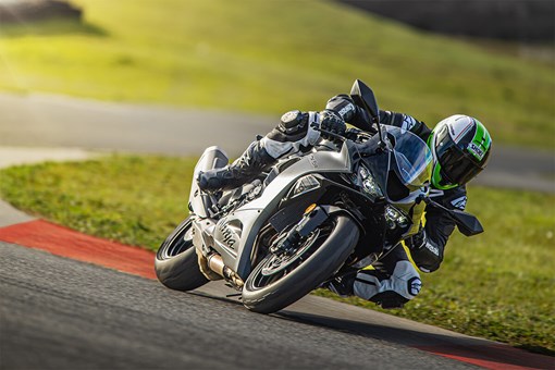 Three-quarter front angle of a person riding a motorcycle leaned over in a corner on a track. opens in a new window