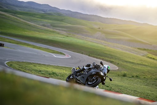 Three-quarter front angle of a person riding a motorcycle through a series of turns on track. opens in a new window