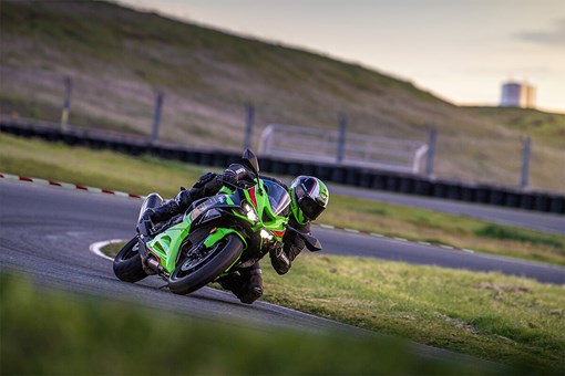 Three-quarter front angle of a person on a motorcycle leaning into a corner on a track. opens in a new window