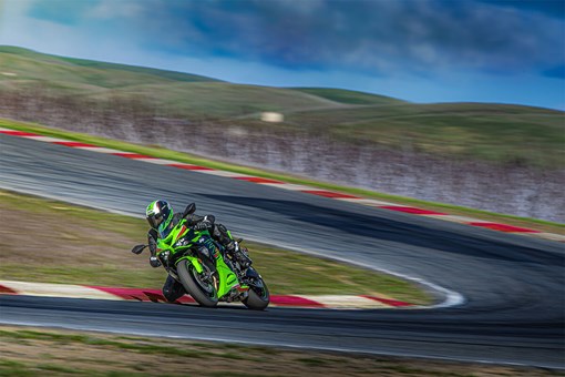Three-quarter front angle of a person on a motorcycle turning on a track. opens in a new window