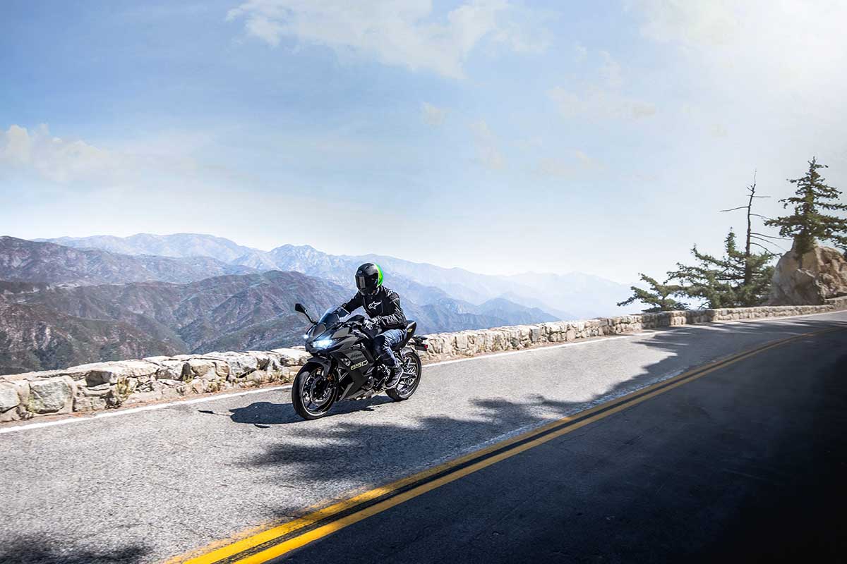 Three-quarter front angle of a person riding a motorcycle on a road.