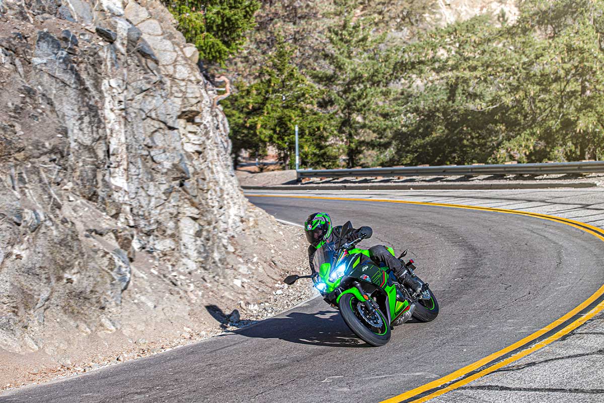 Three-quarter front angle of a person riding a motorcycle on a winding road.