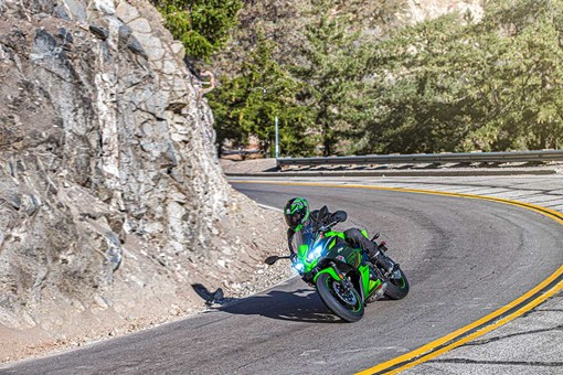 Three-quarter front angle of a person riding a motorcycle on a winding road. opens in a new window