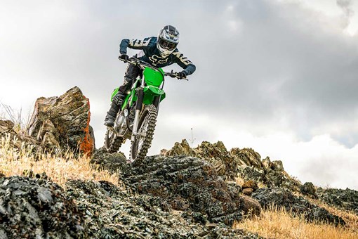 Front angle of a person riding a green motorcycle off-road. opens in a new window