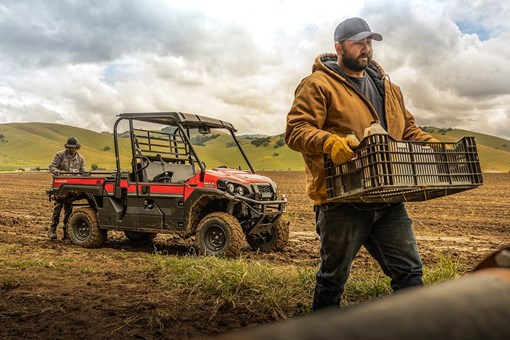 Three-quarter front angle of two people unloading a side x side off-road. opens in a new window