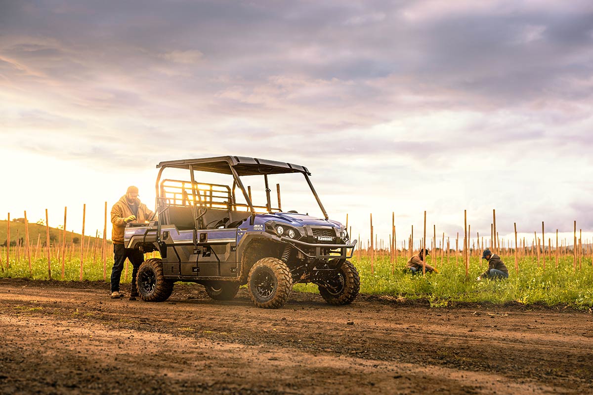 Three-quarter front angle of a person loading a side x side near a field.
