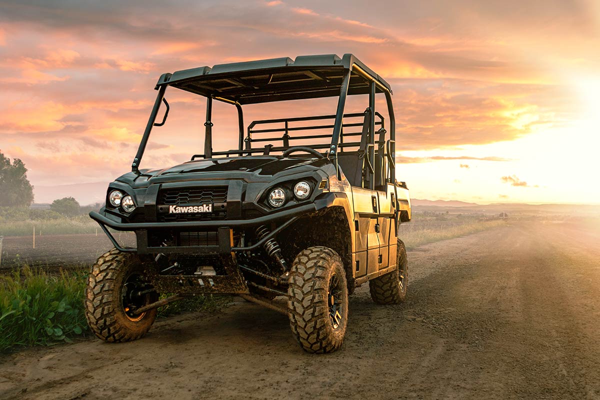 Three-quarter front angle of a side x side parked off-road with the sunset behind it.
