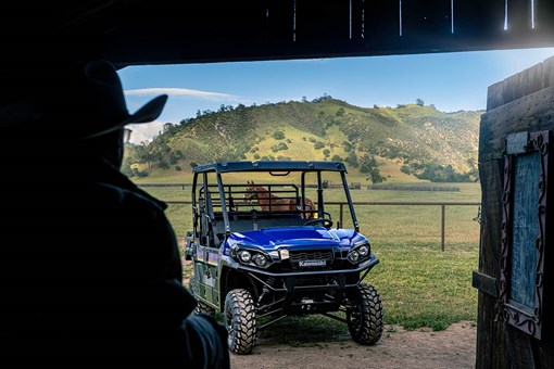 Three-quarter front angle of a parked side x side off-road with hills in the background. opens in a new window