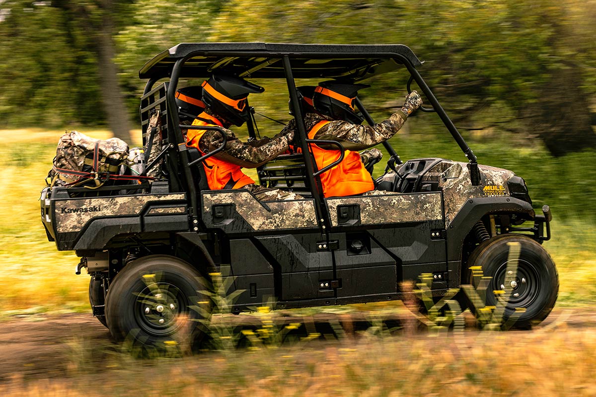 Side angle of a person driving a side x side with three passengers off-road.