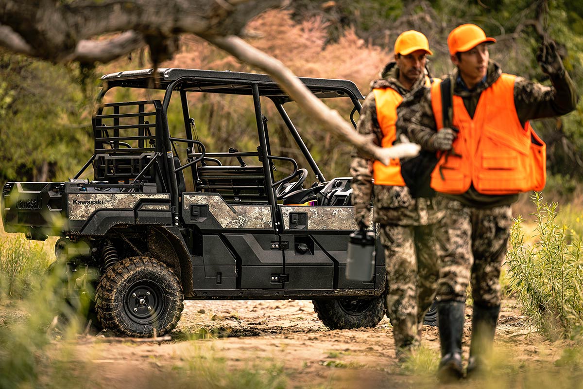 Three-quarter rear angle of two people walking away from a parked side x side off-road.