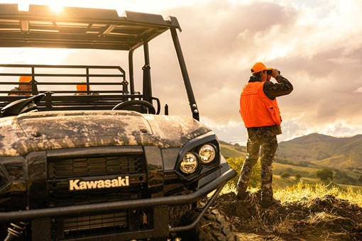Front angle of a person standing next to a parked side x side off-road. opens in a new window