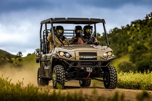 Three-quarter front angle of a person driving a side x side with three passengers off-road. opens in a new window