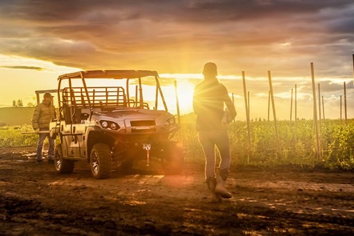 Three-quarter front angle of a parked side x side off-road with a sunset behind it. opens in a new window
