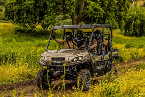 Three-quarter front angle of a person driving a side x side on a dirt trail. opens in a new window