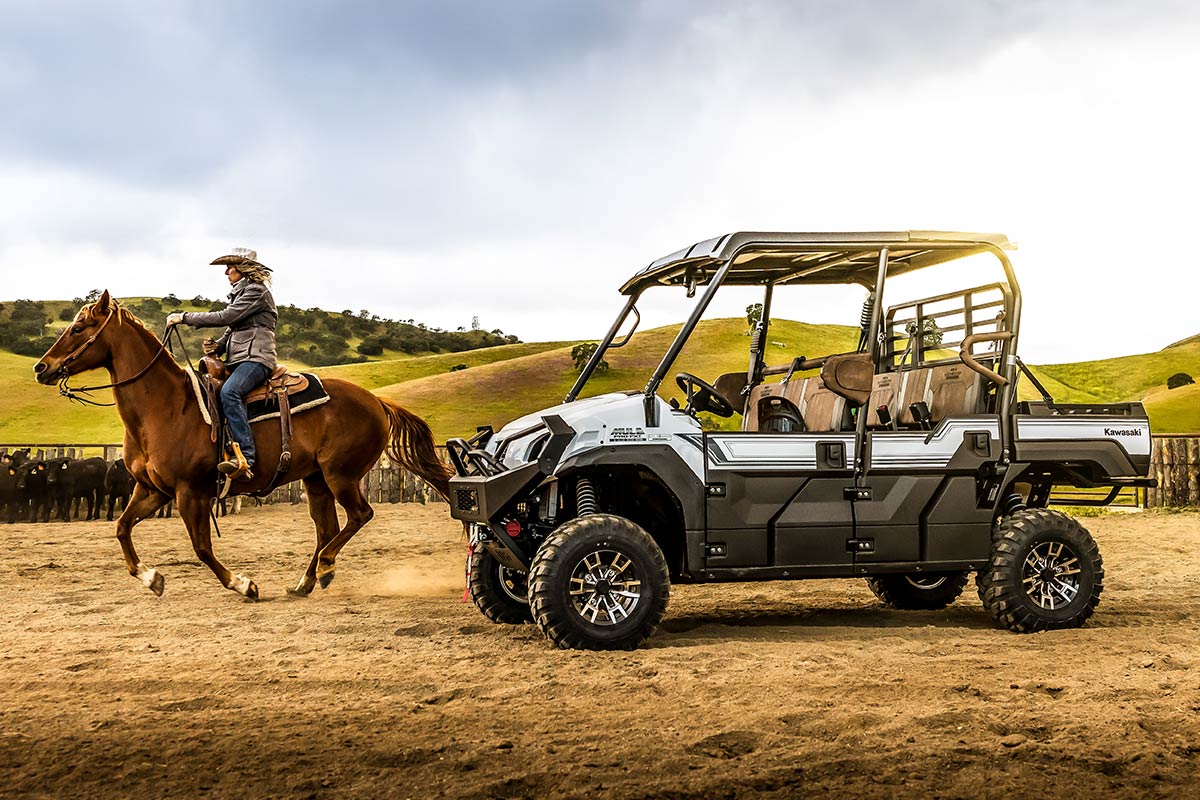 Side angle of a side x side parked off-road next to a person riding a horse.