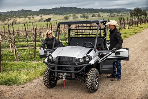 Front angle of two people entering a side x side parked on a trail. opens in a new window