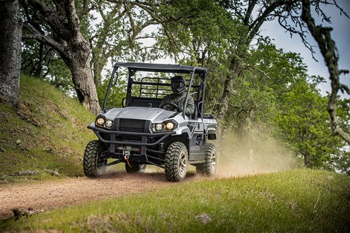 Three-quarter front angle of a person driving a side x side on a trail. opens in a new window