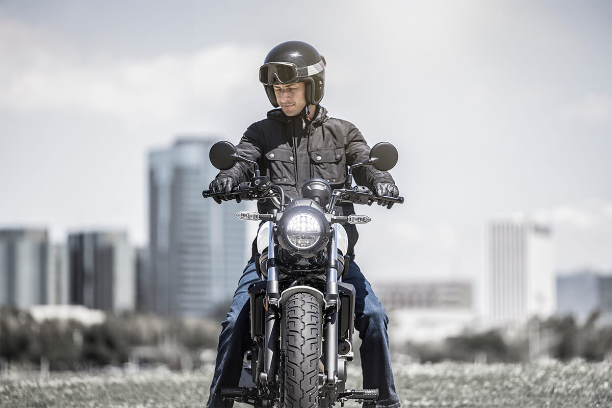 Front angle of a person on a motorcycle in a city.