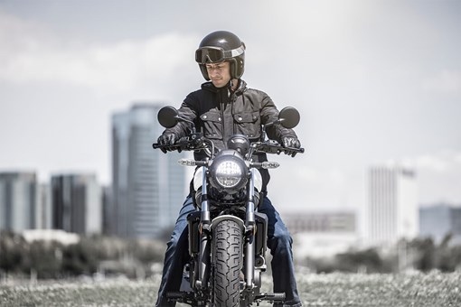 Front angle of a person on a motorcycle in a city. opens in a new window