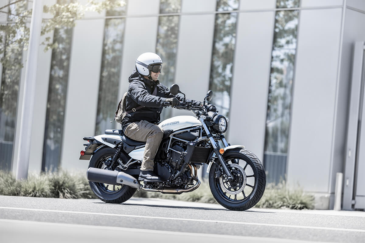 Side angle of a person riding a motorcycle on a street.