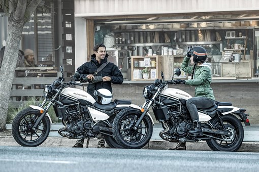 Side angle of two people next to and on motorcycles. opens in a new window