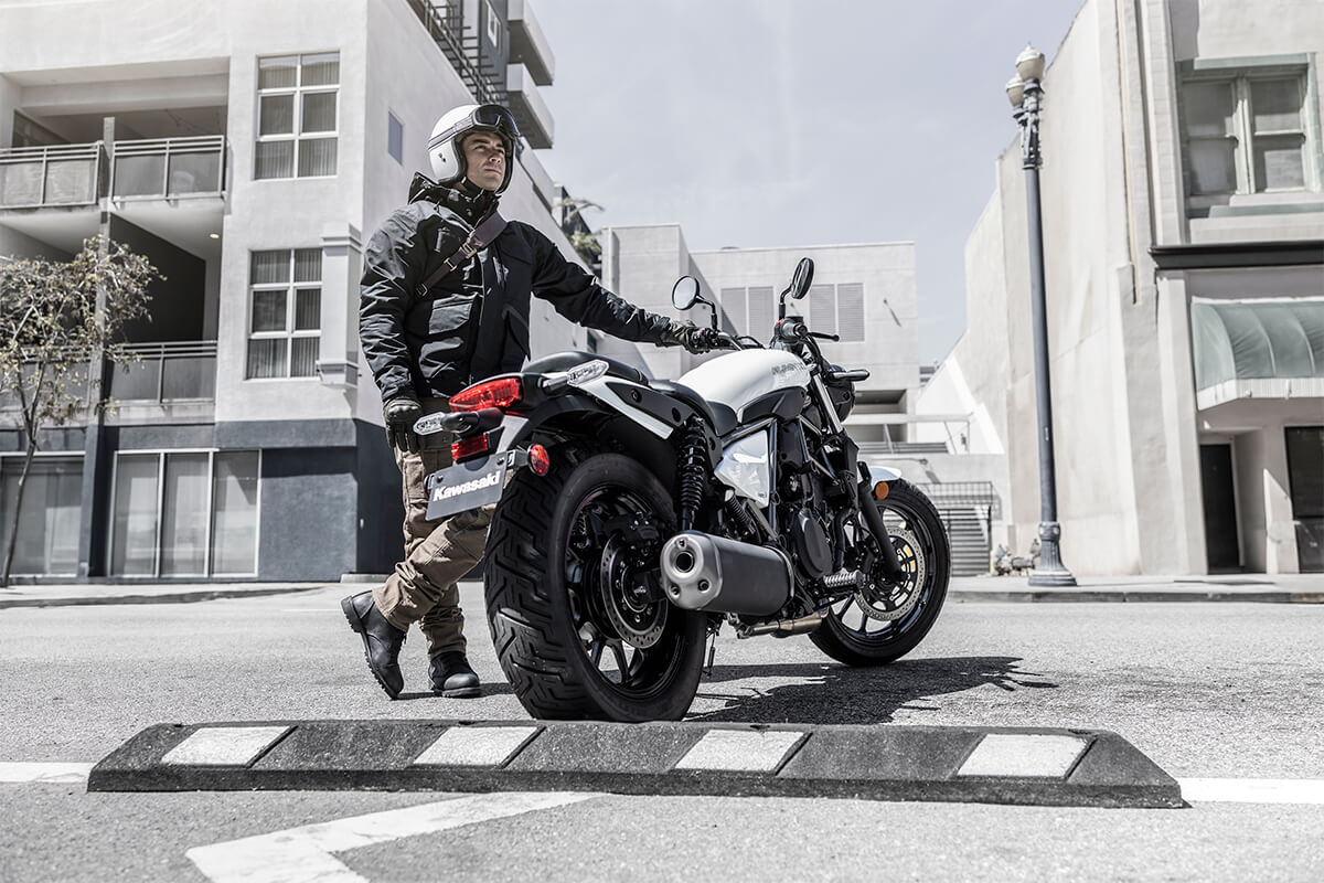 Three-quarter rear angle of a person next to a motorcycle.