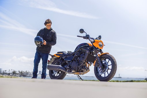 Side angle of a person standing next to a motorcycle. opens in a new window