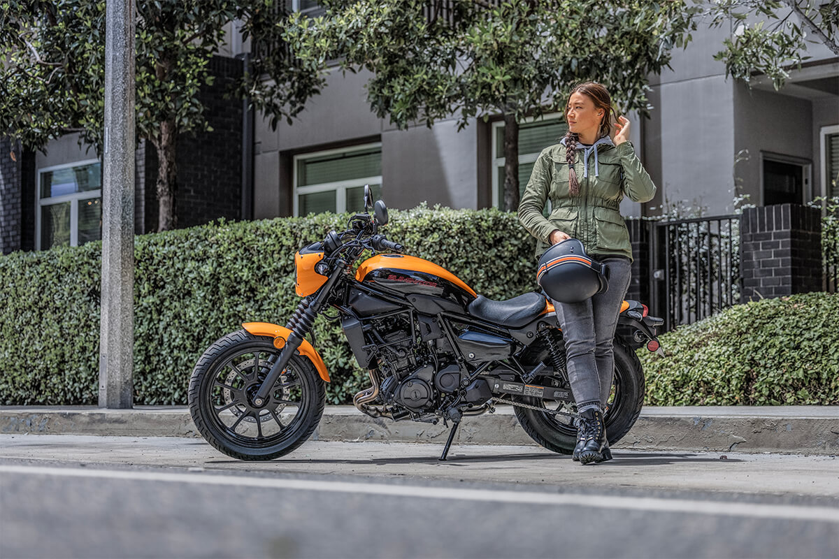 Profile angle of a person next to a parked motorcycle.