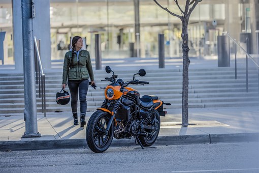 Three-quarter front angle of a person next to a motorcycle. opens in a new window