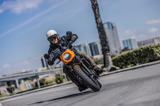 Front angle of a person riding a motorcycle on a city street. opens in a new window