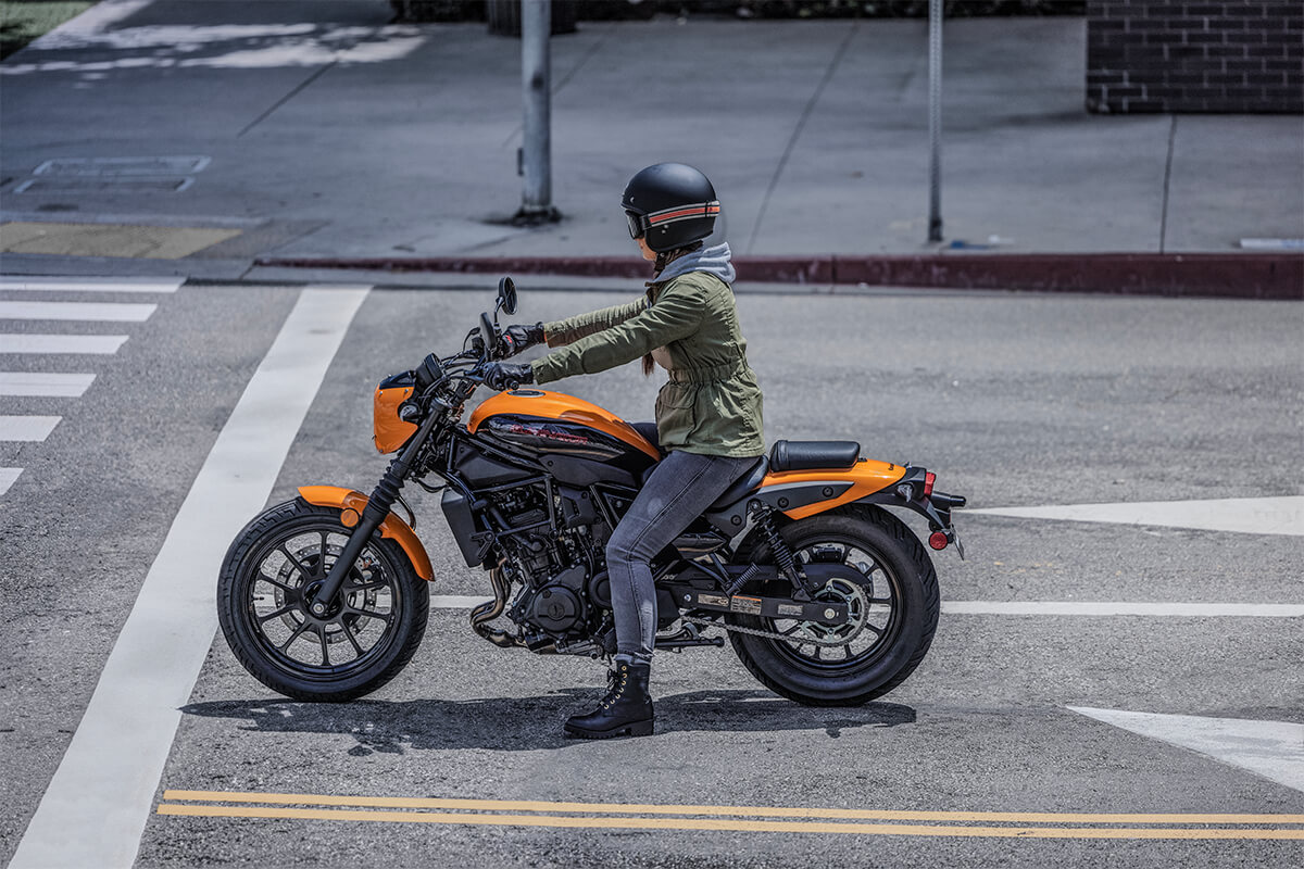 Side angle of a person on a motorcycle on a city street.