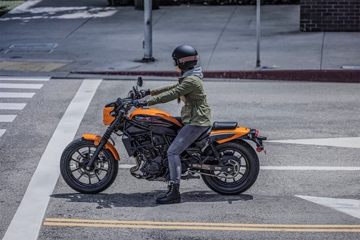 Side angle of a person on a motorcycle on a city street. opens in a new window