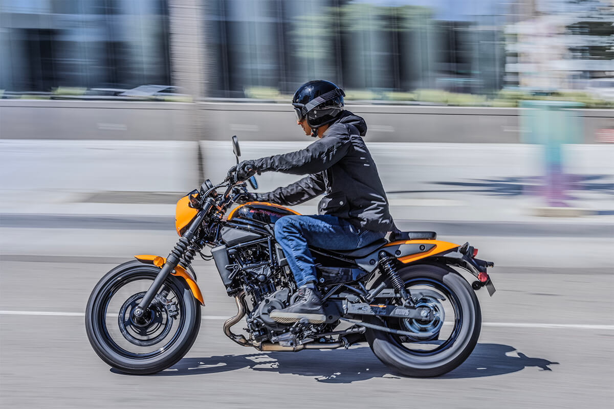 Profile angle of a person riding an orange motorcycle in the city.