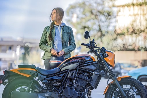 Profile angle of a person standing next to a motorcycle. opens in a new window