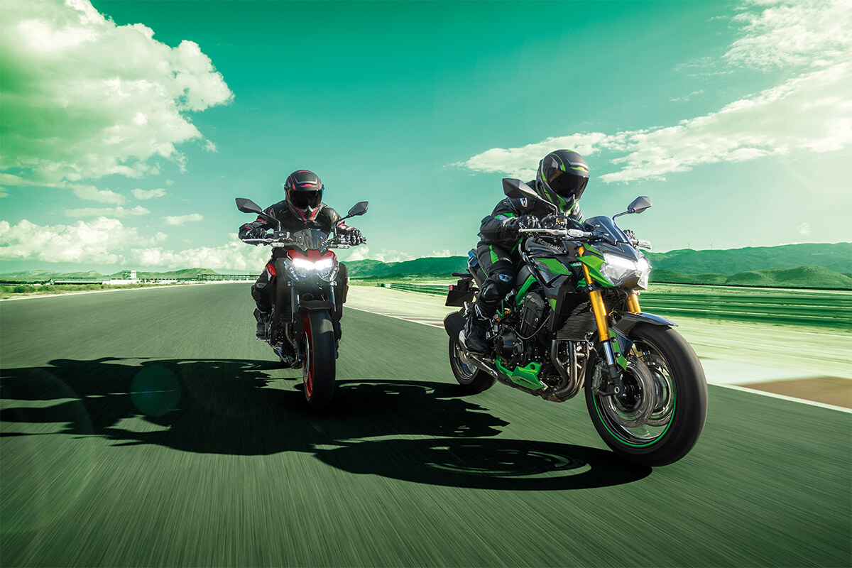 Front angle of two people riding motorcycles on a racetrack.