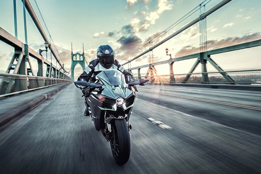Front angle of a person riding a motorcycle on a bridge. opens in a new window