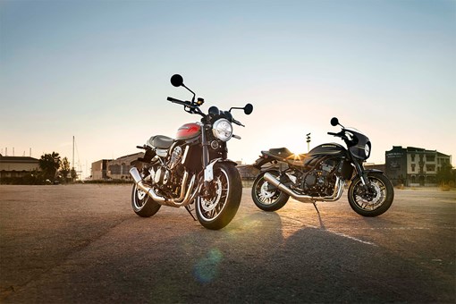 Three-quarter front angle of two motorcycles parked in a lot. opens in a new window