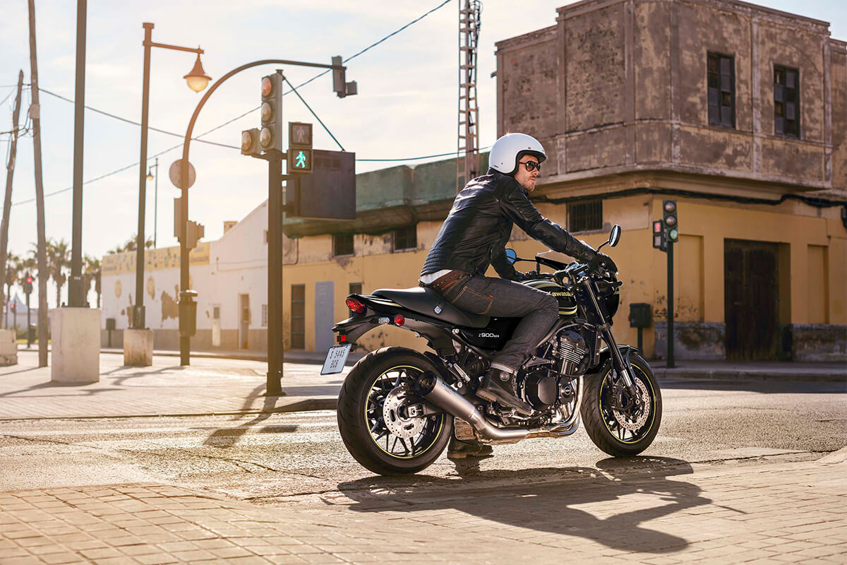 Side angle of a person on a motorcycle stopped at a red light.
