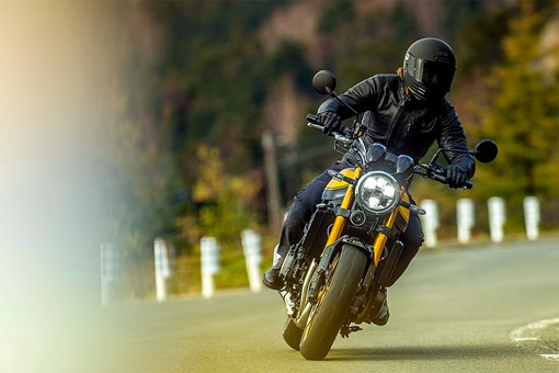 Front angle of a person riding a motorcycle on a road. opens in a new window